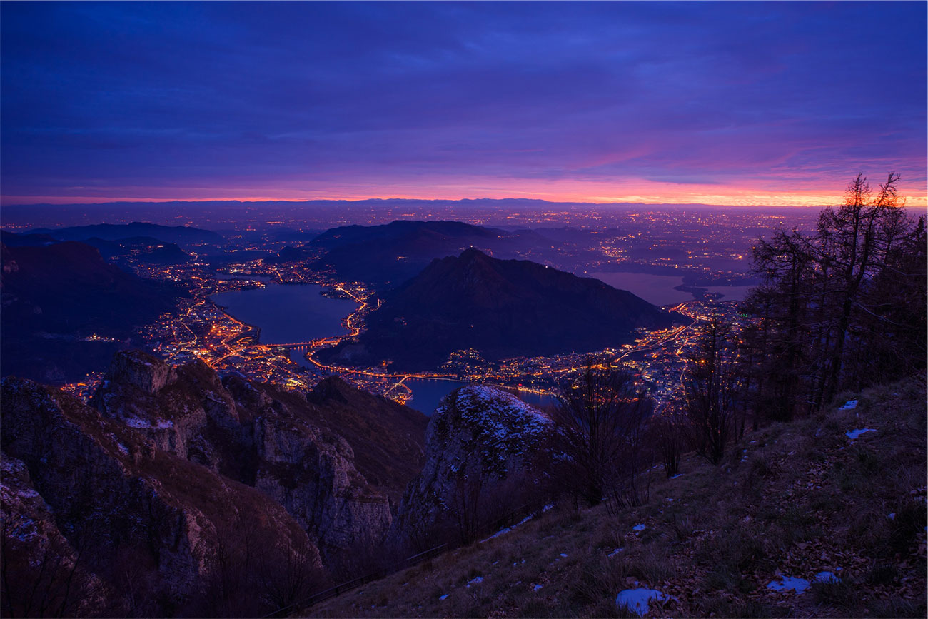 Berglandschaft mit beleuchteten, miteinander verbundenen Siedlungen am See